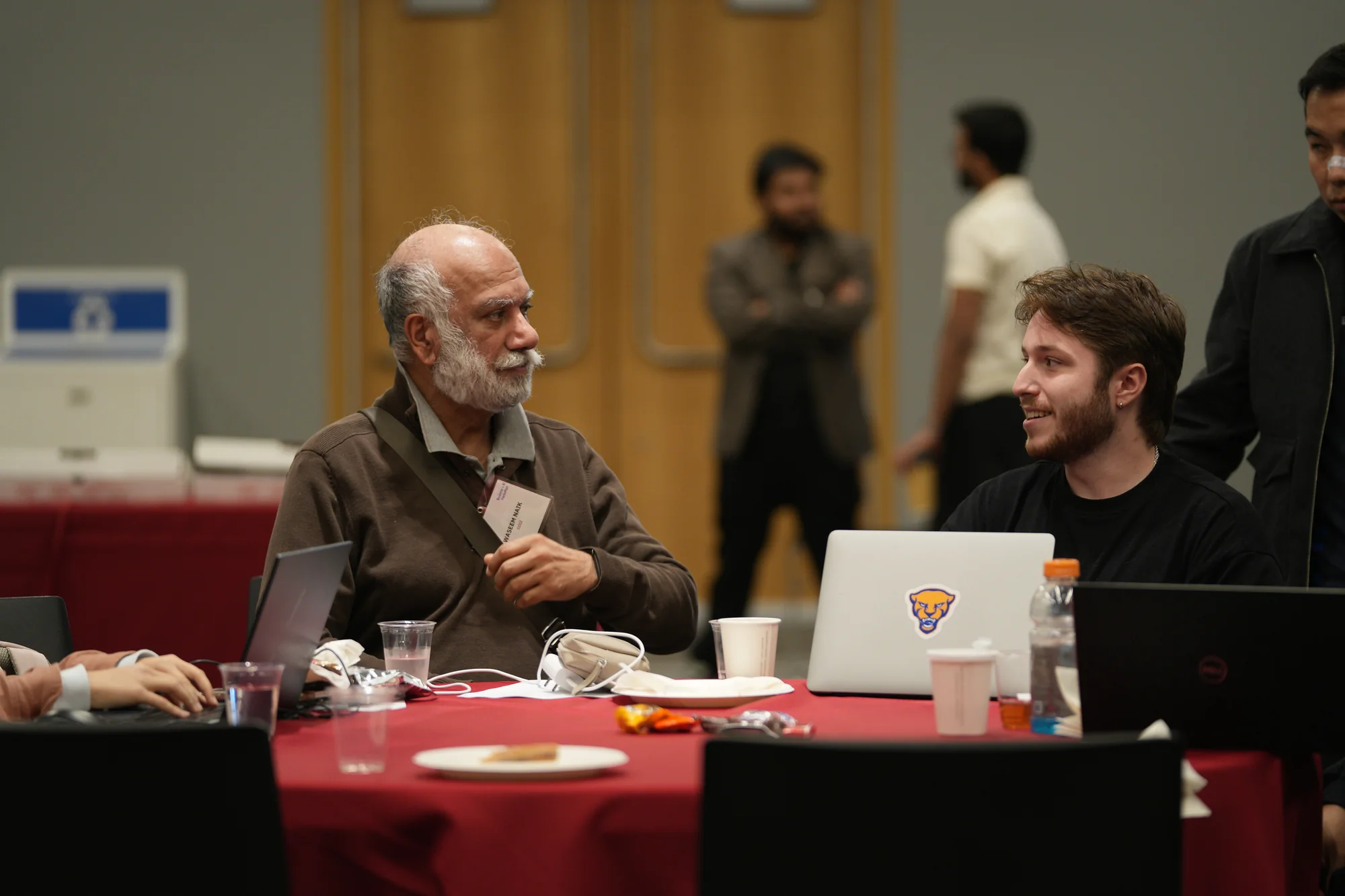 Hackathon team members working together at a table with laptops